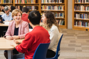 Faculty Registrar Helen Bright sitting at a table with two engineering students in the Engineering & Computer Science Library.