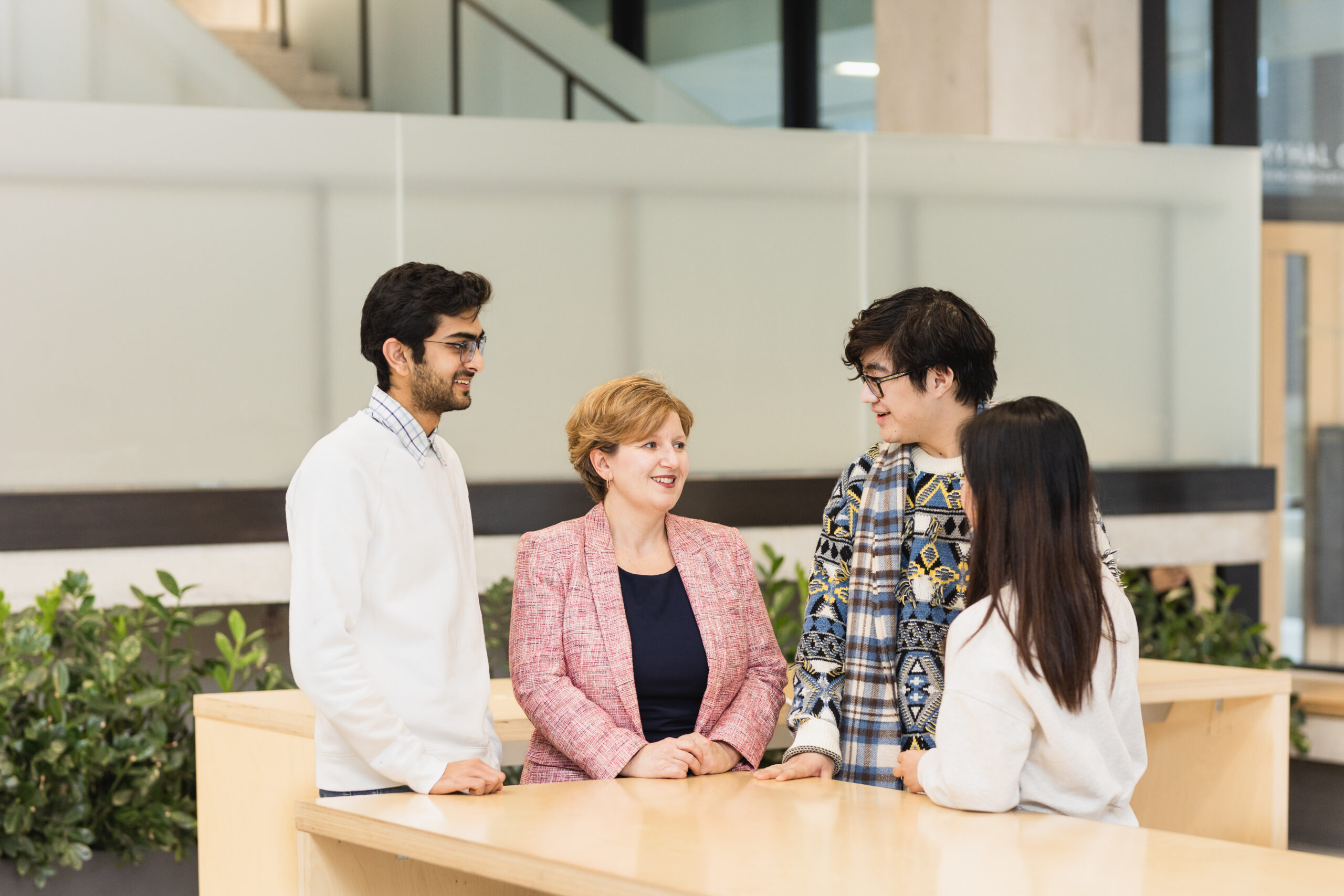 Faculty Registrar Helen Bright standing with three engineering students around a table.