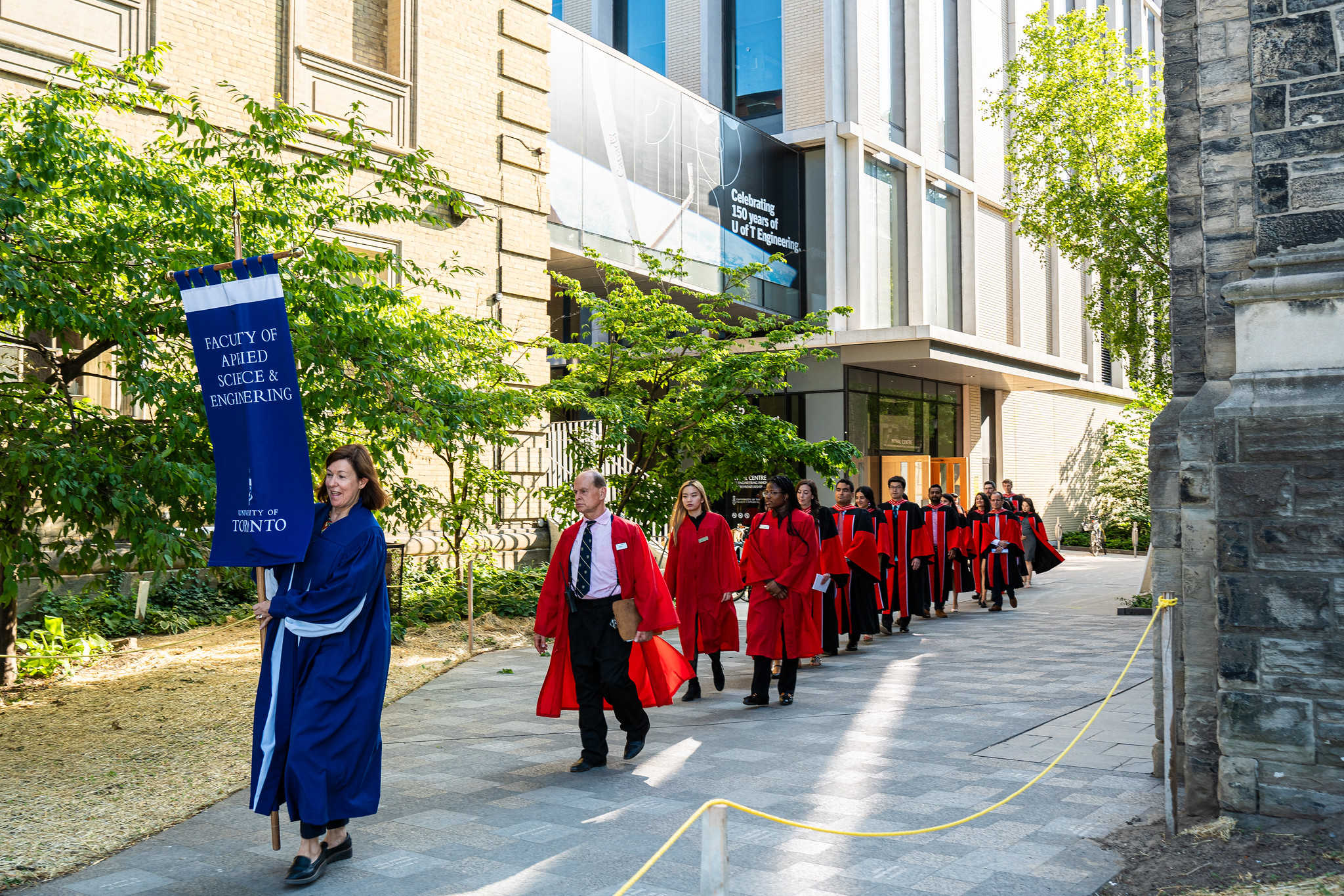 Image shows graduating students walking in a line outside of Myhal Centre.