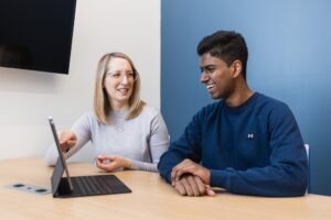 Student sitting with an academic advisor looking at a computer screen while smiling.