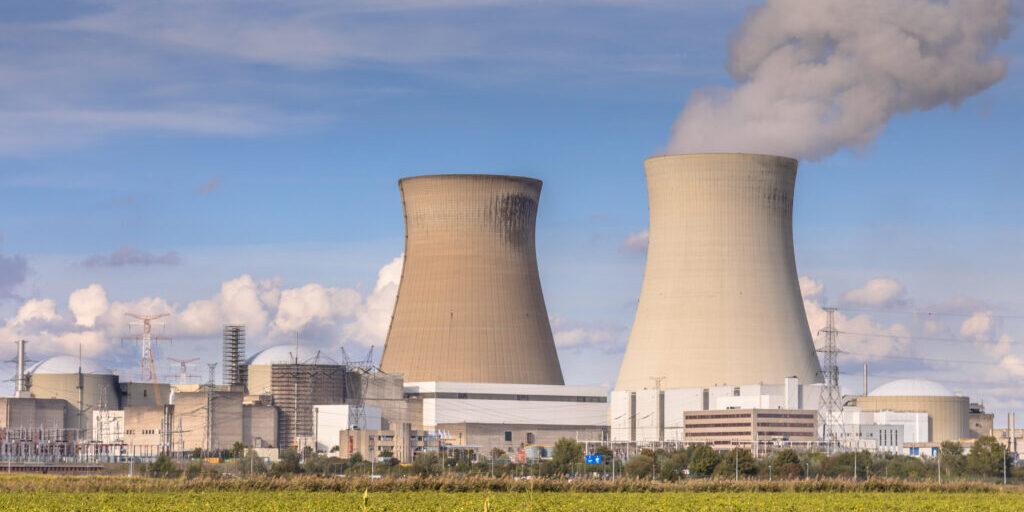 Nuclear power plant with steaming cooling towers under blue summer sky in Belgium