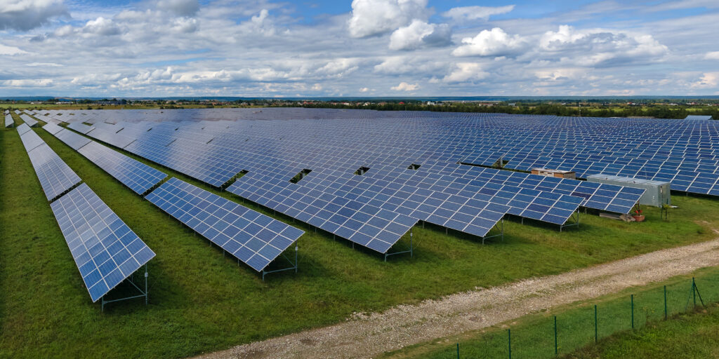 Aerial view of large sustainable electrical power plant with rows of solar photovoltaic panels for producing clean electric energy. Concept of renewable electricity with zero emission.